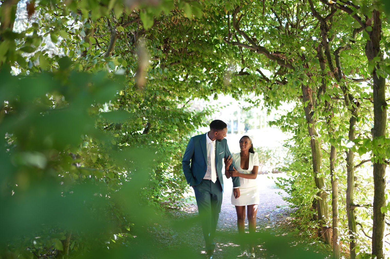 Couple de mariés marchant sous une allée d'arbres