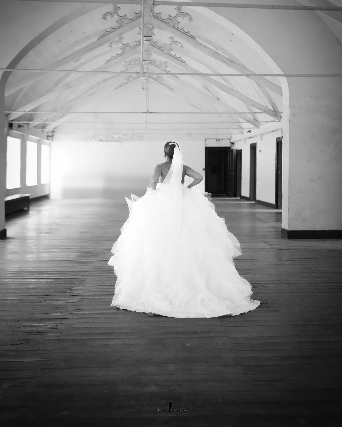 La mariée de dos dans une grande salle voûtée