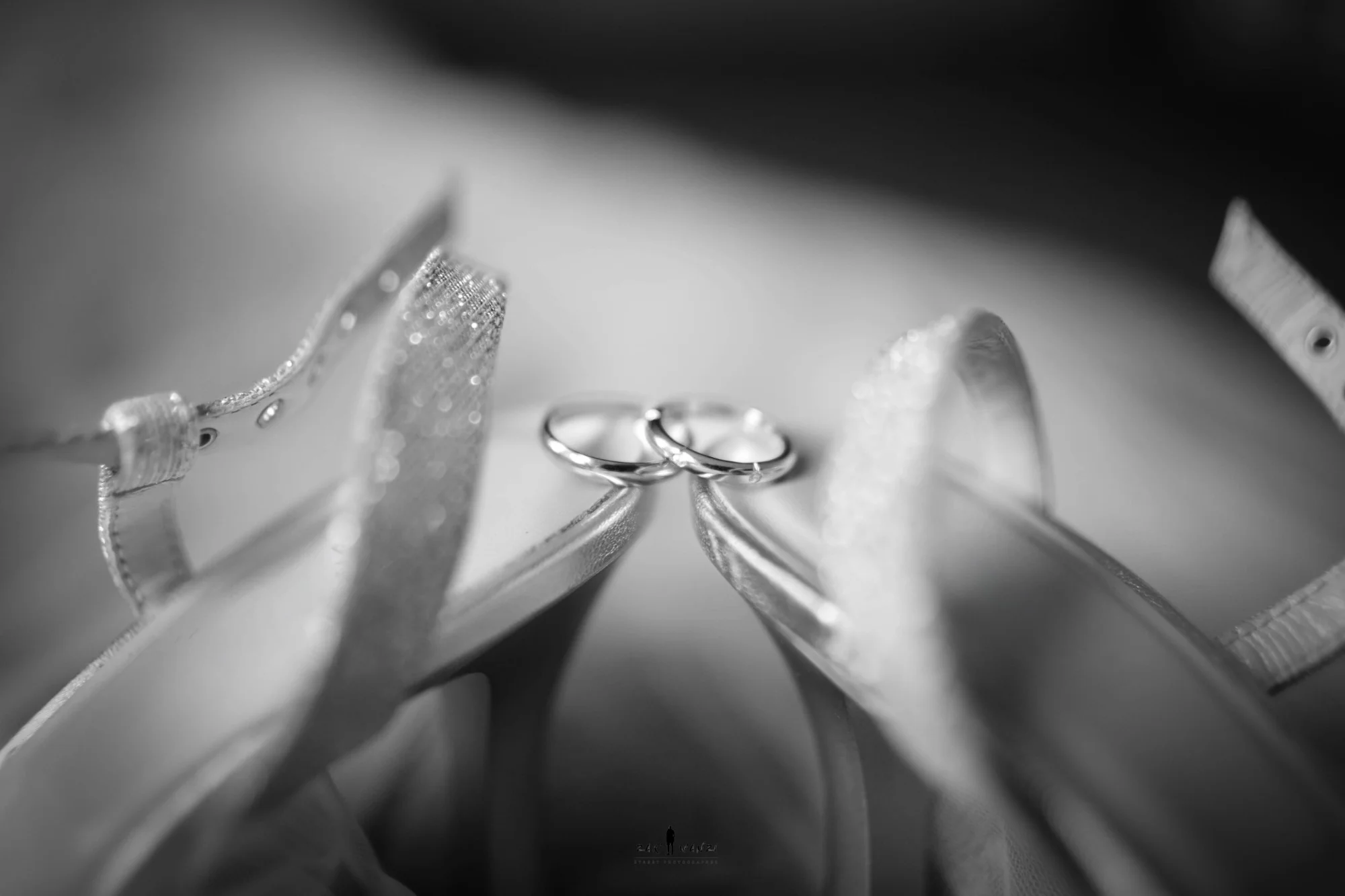 Alliances posées entre les escarpins de la mariée, détail de mariage en noir et blanc