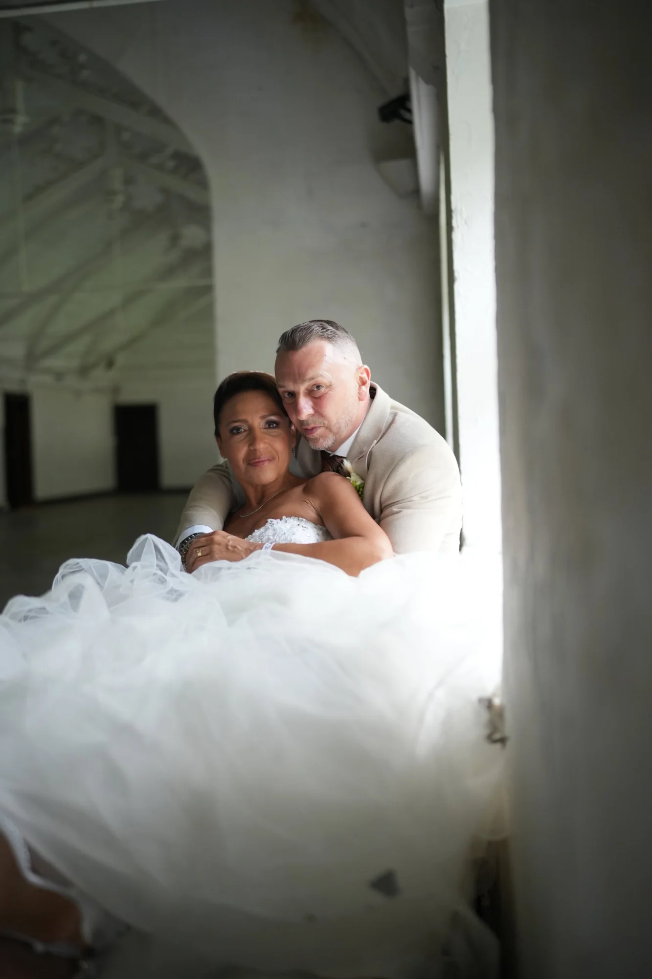 Les mariés enlacés près d'une fenêtre, portrait de couple naturel