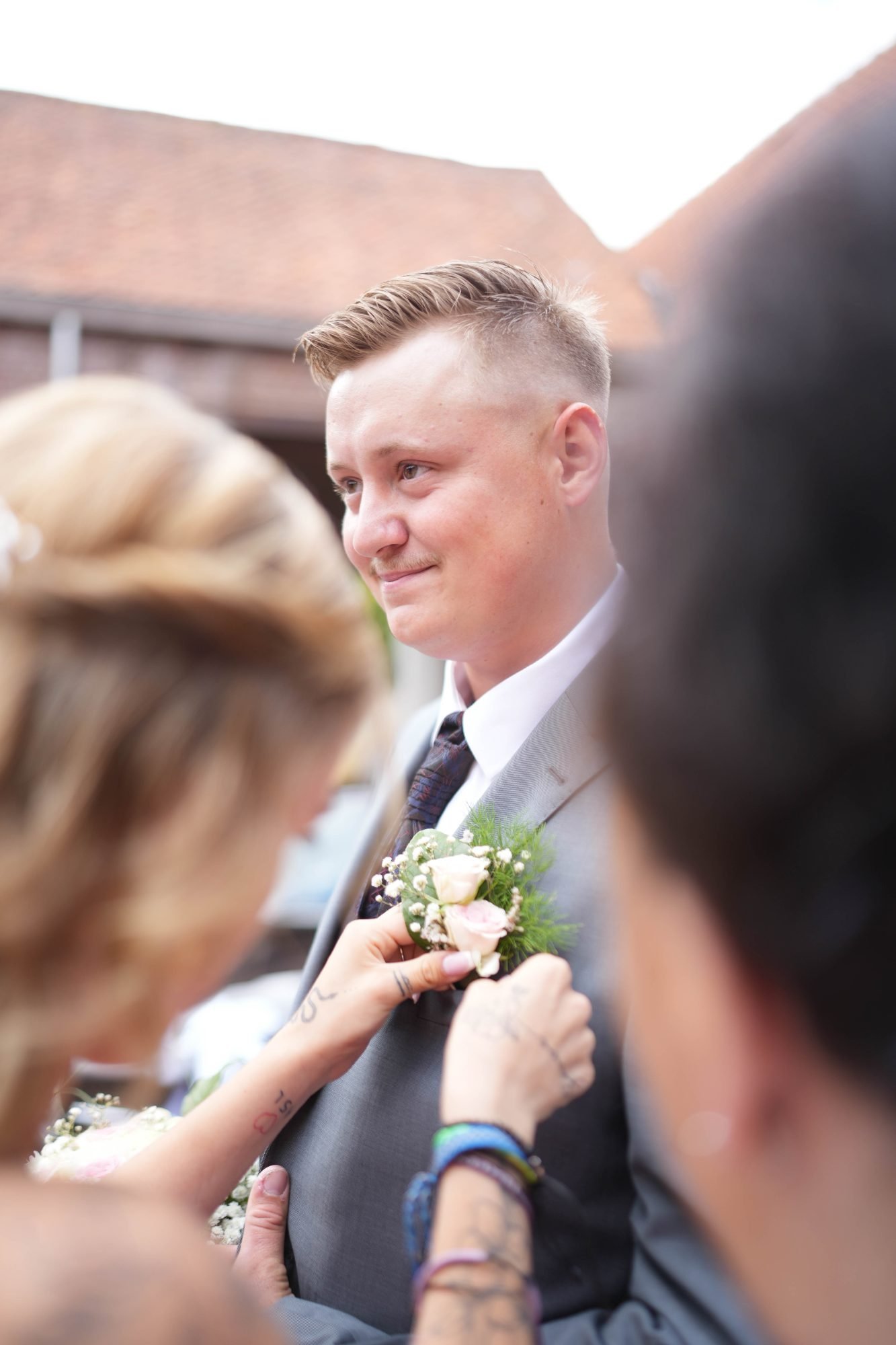 Le marié ému pendant qu'on accroche sa boutonnière