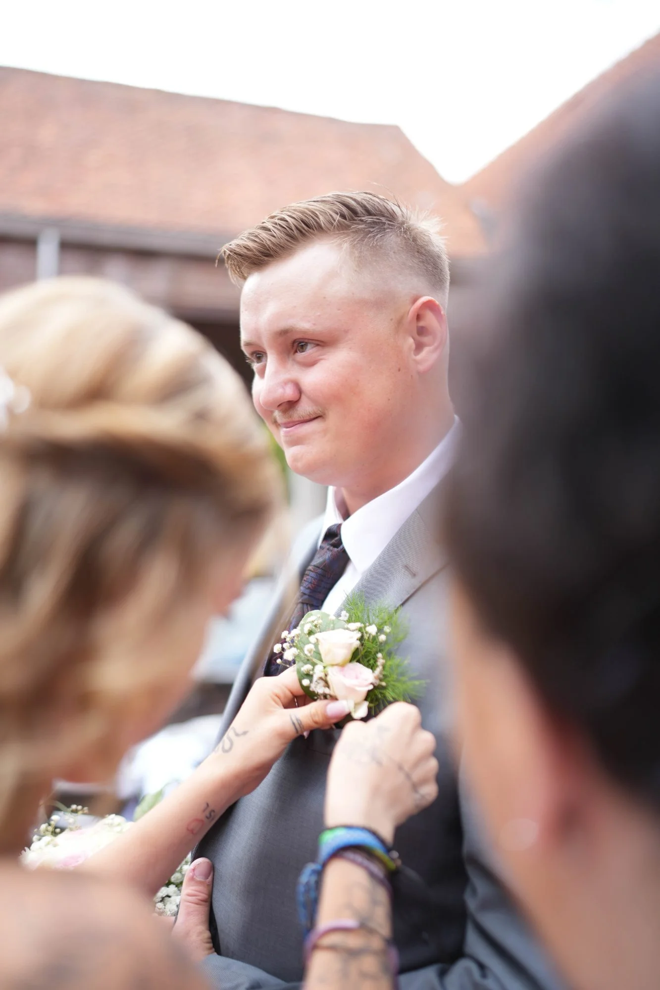 Le marié ému pendant qu'on accroche sa boutonnière