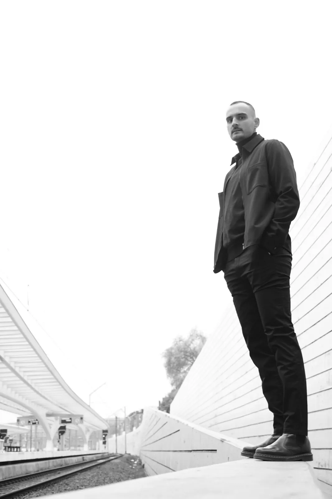 Portrait en pied, noir et blanc, sous la verrière de la gare des Guillemins