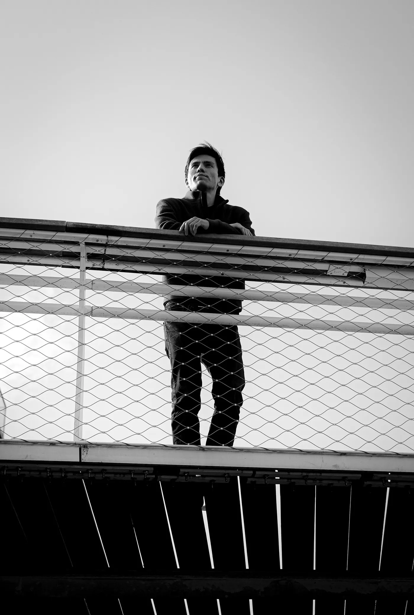 Portrait accoudé à une passerelle, ciel clair