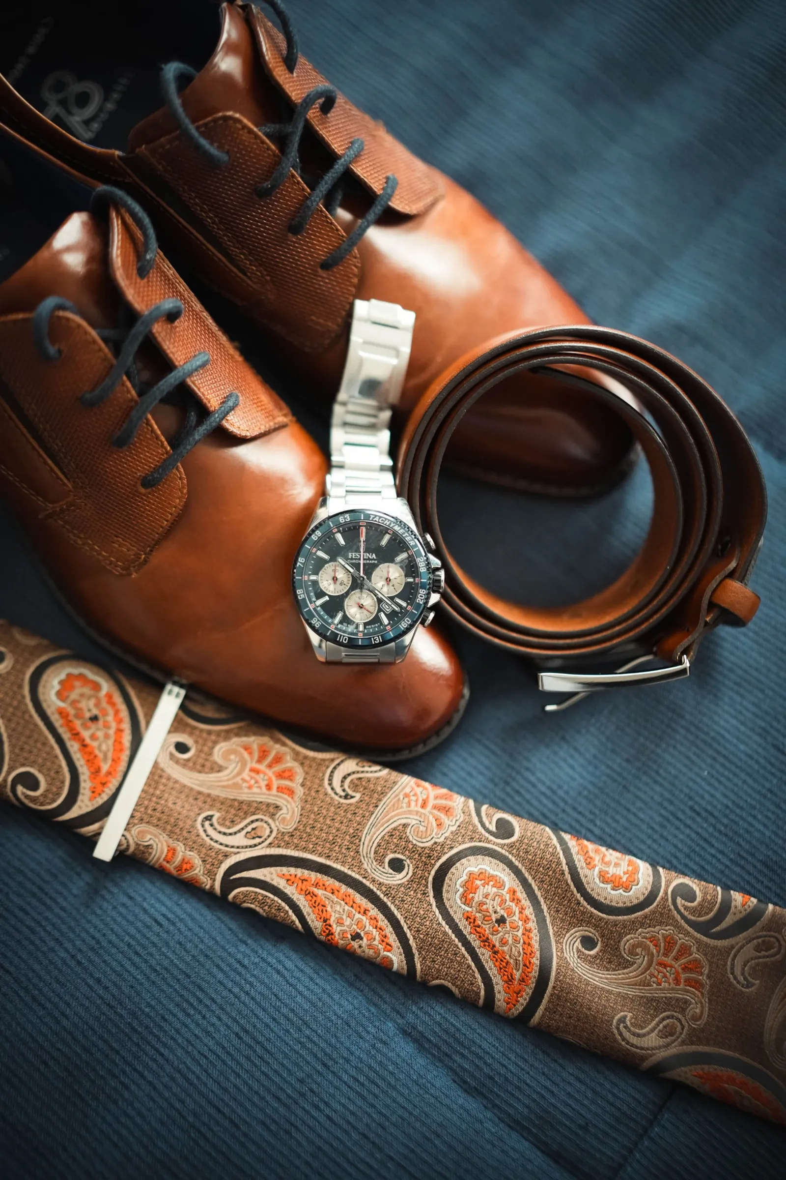 Chaussures et accessoires du marié posés sur le lit